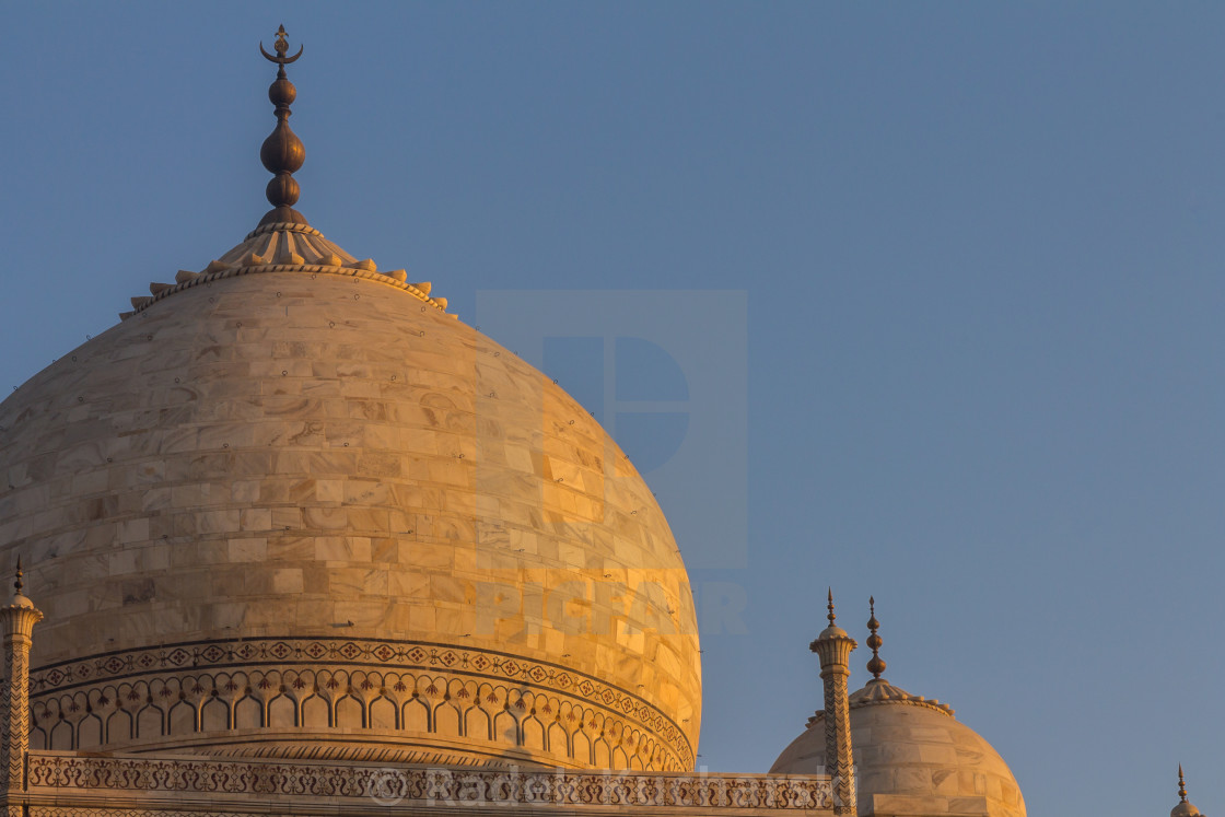 "Taj Mahal's dome lit by the golden light of the rising sun" stock image