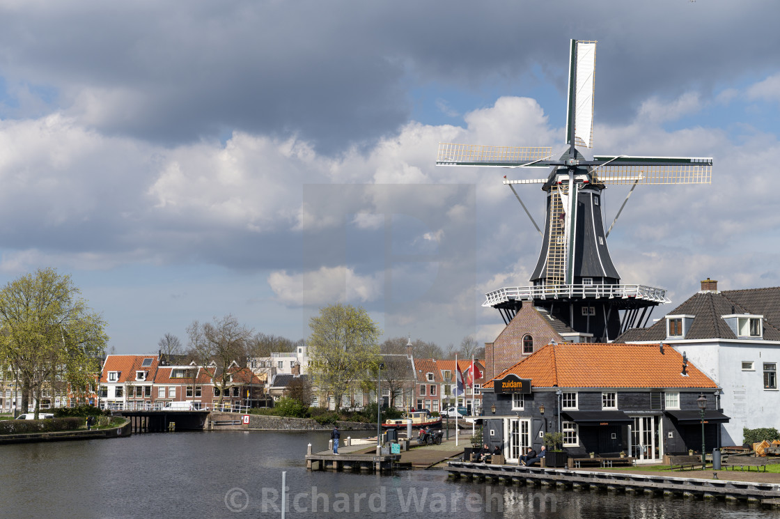 "Haarlem The Netherlands 25th March 2024 Haarlem The Netherlands Windmill Molen De Adriaan on the River Spaarne with someone half way up the lower sail unfurling the canvas." stock image