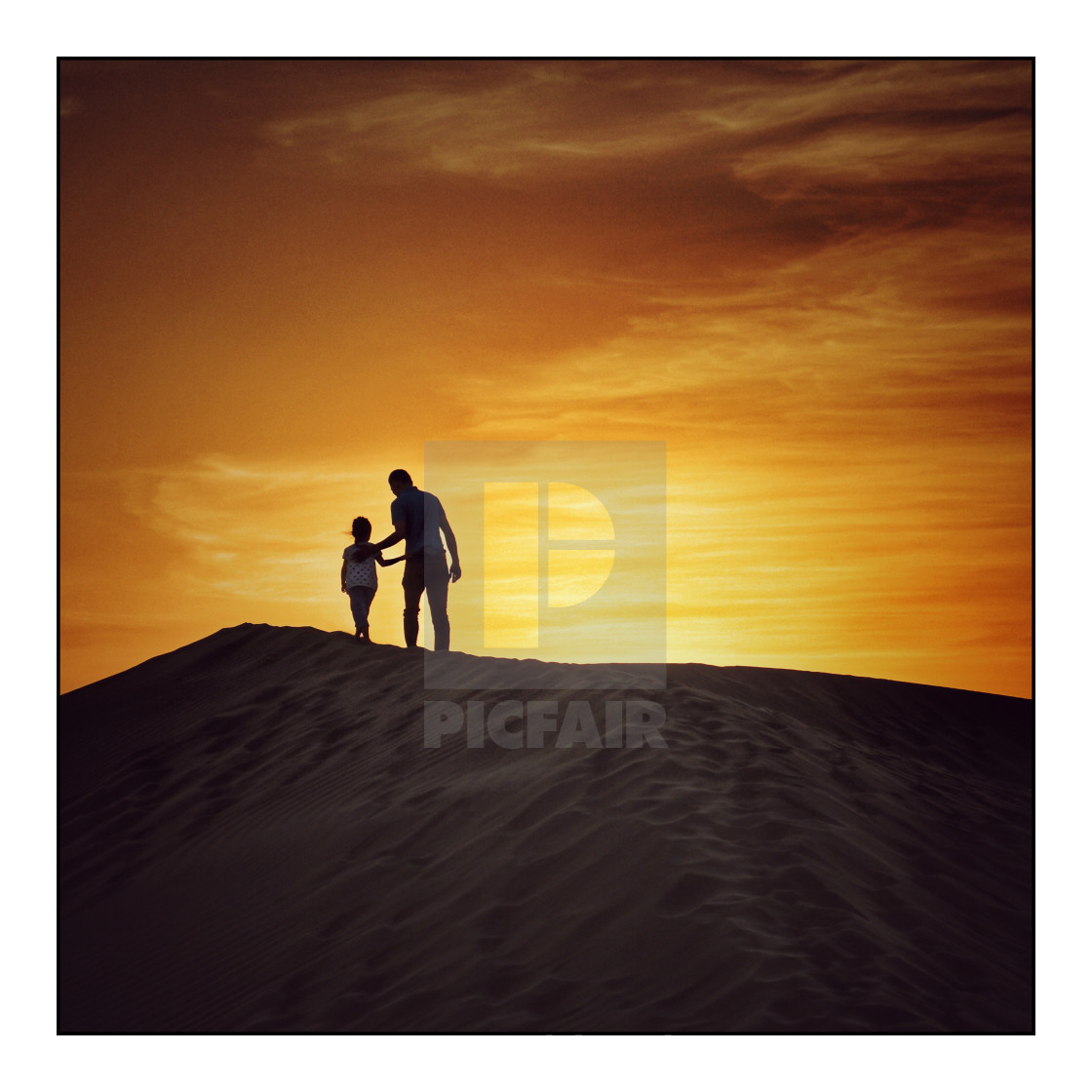 "Man and boy on sand dune at sunset" stock image