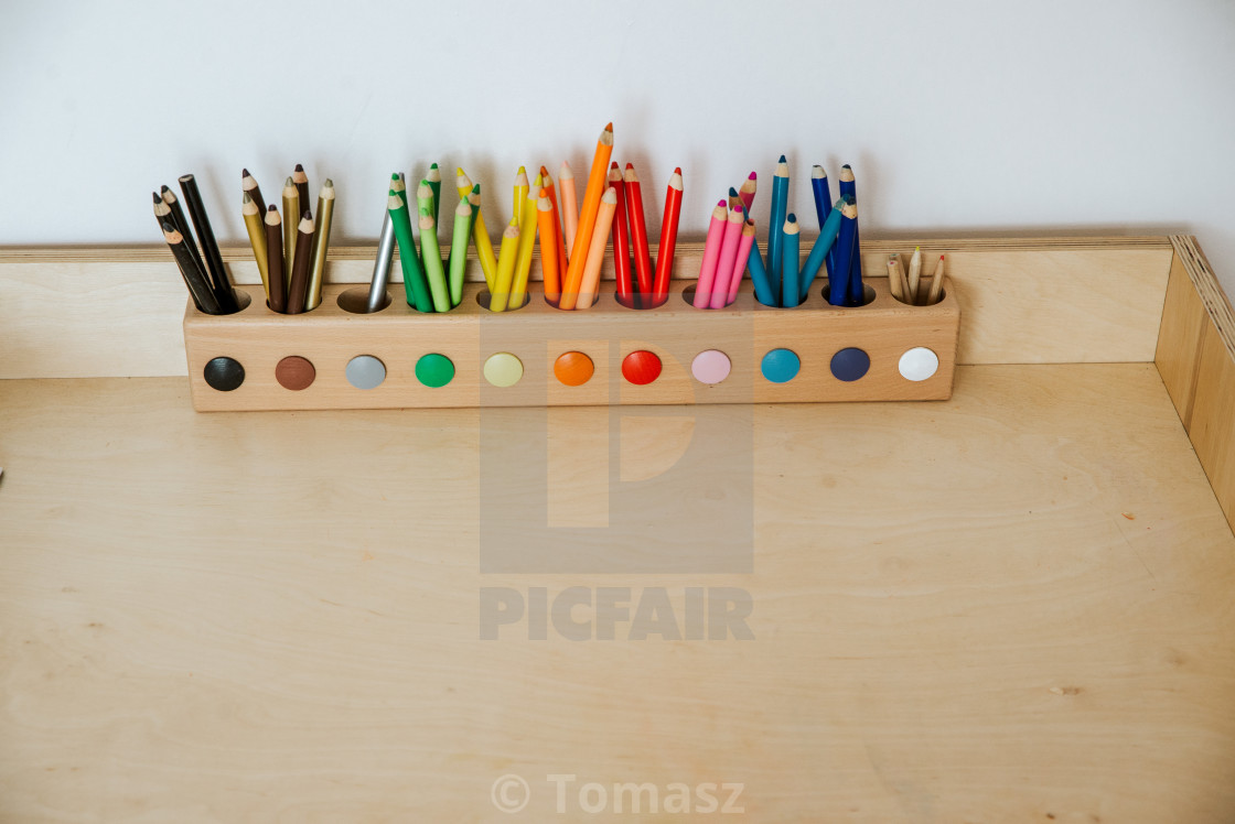 "colored pencils in a container on a wooden table" stock image