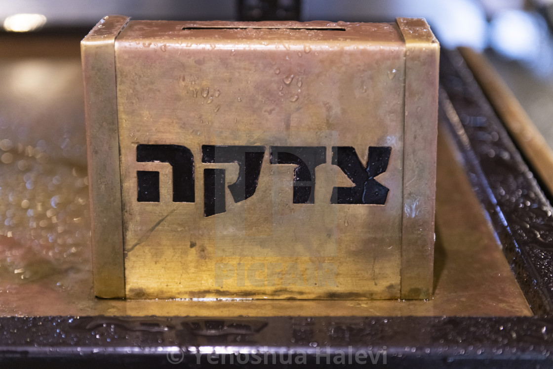 "A golden, metal tzedakah (a Hebrew word which means "charity") collection box sitting on a table in Jerusalem outside in the rain." by Yehoshua Halevi - $6.09 "A golden, metal tzedakah (a Hebrew word which means "charity") collection box sitting on a table in Jerusalem outside in the rain." stock image