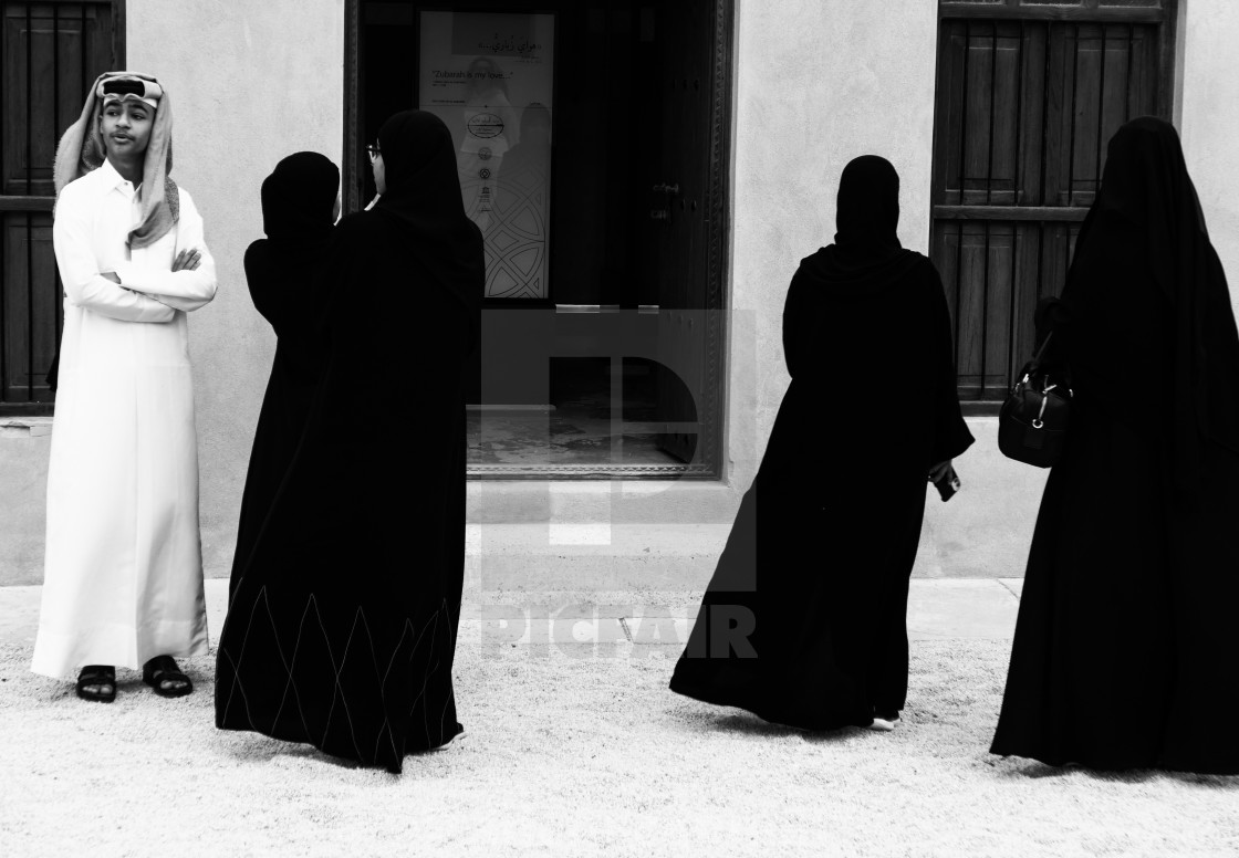 "a local man and three women at the Al Zubara fort in black and white" stock image