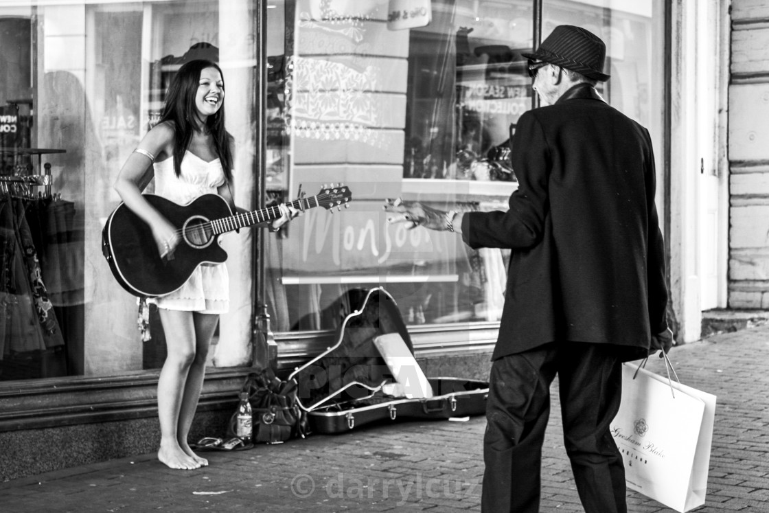 "A girl busking in bare feet in the street shares a joyous moment with a well dressed, elegant man in Brighton, UK." by darrylcuz - £6.20 "A girl busking in bare feet in the street shares a joyous moment with a well dressed, elegant man in Brighton, UK." stock image