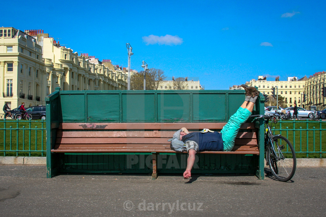 "A man asleep on a bench with his bycycle beside him in Hove, UK." by darrylcuz - £6.20 "A man asleep on a bench with his bycycle beside him in Hove, UK." stock image