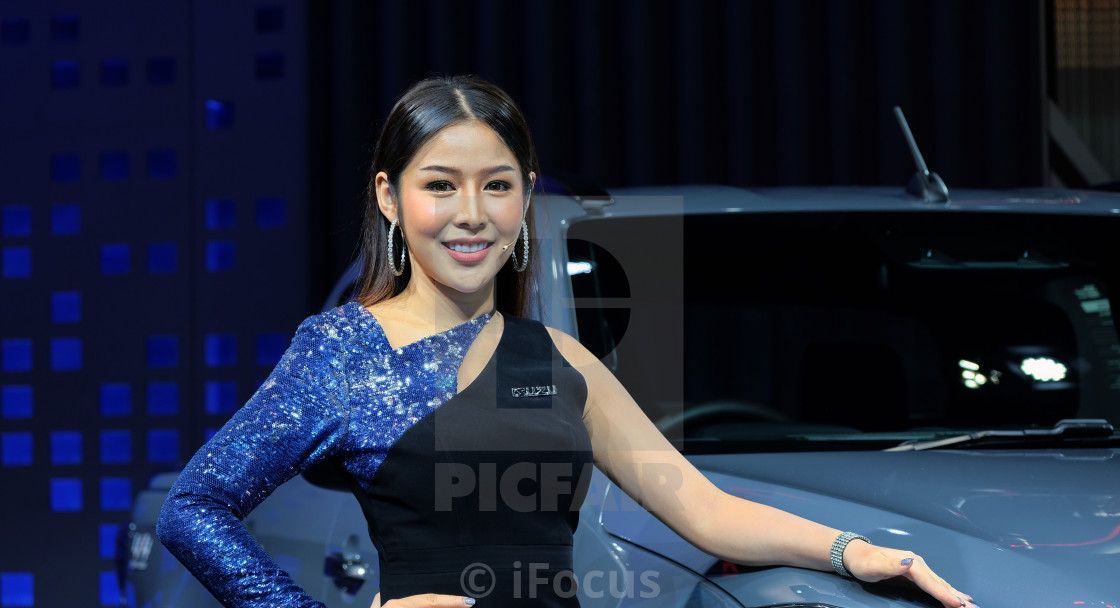 "Pretty presenter stands next to a car" stock image