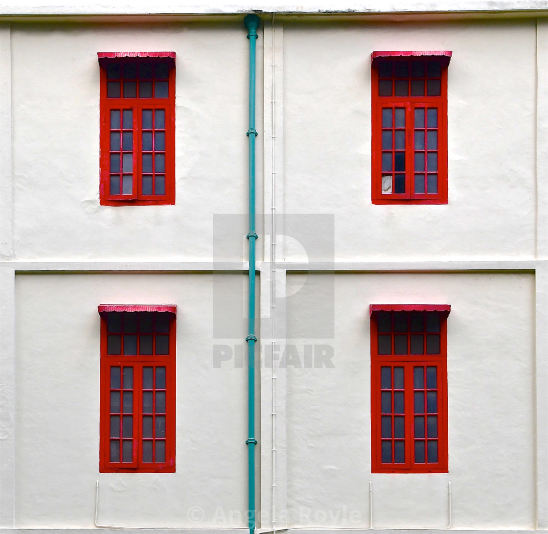 "Four red windows on a white stone wall" stock image