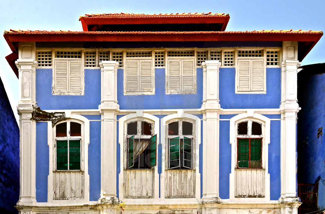 "Light blue pernakan shophouse with green windows and white shutters." stock image