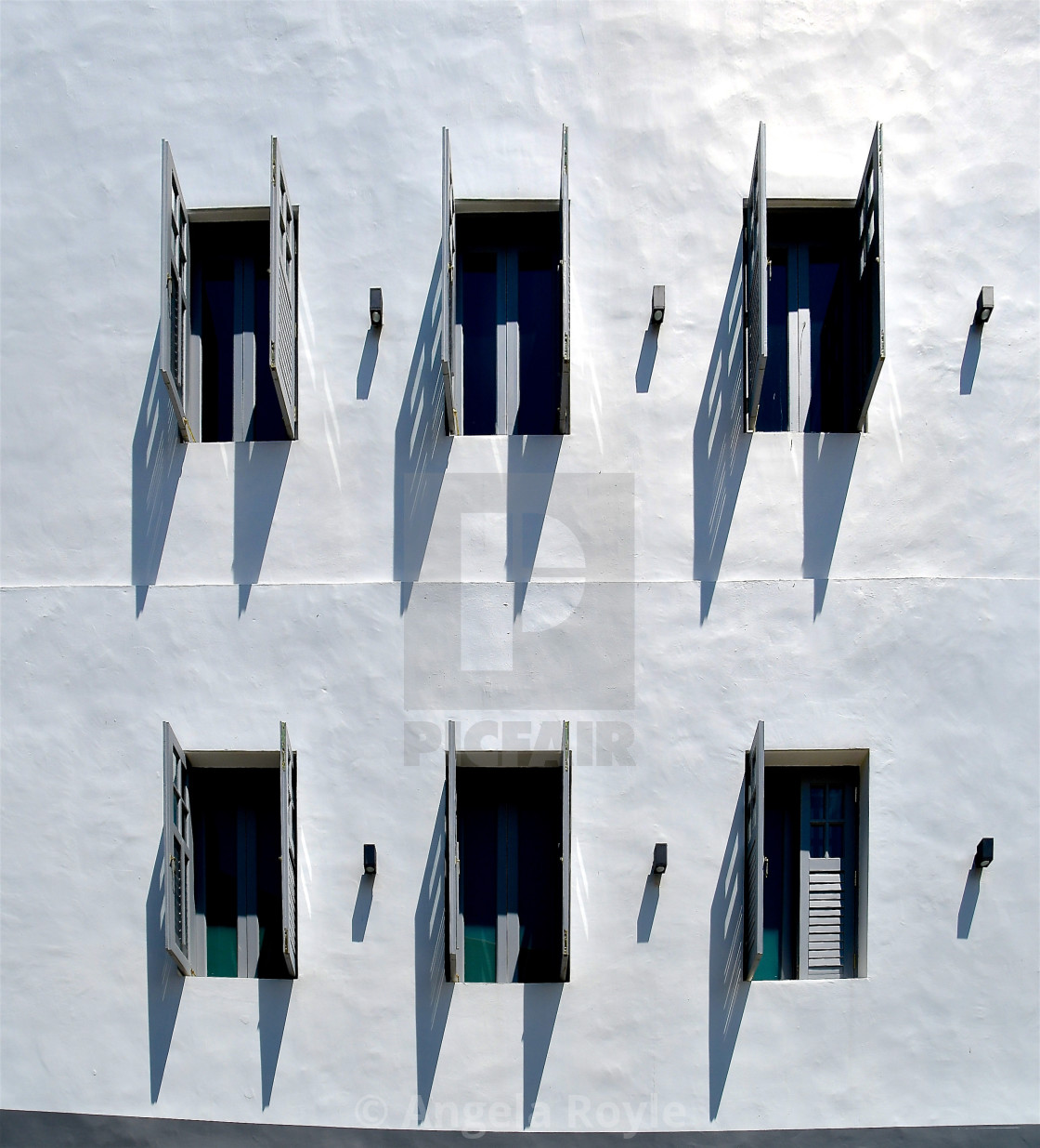 "White stone mediterranean building with grey wooden louvred shutters." stock image