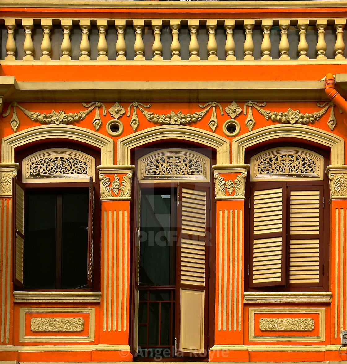 "A restored orange Chinese peranakan shop house with brown shutters" stock image