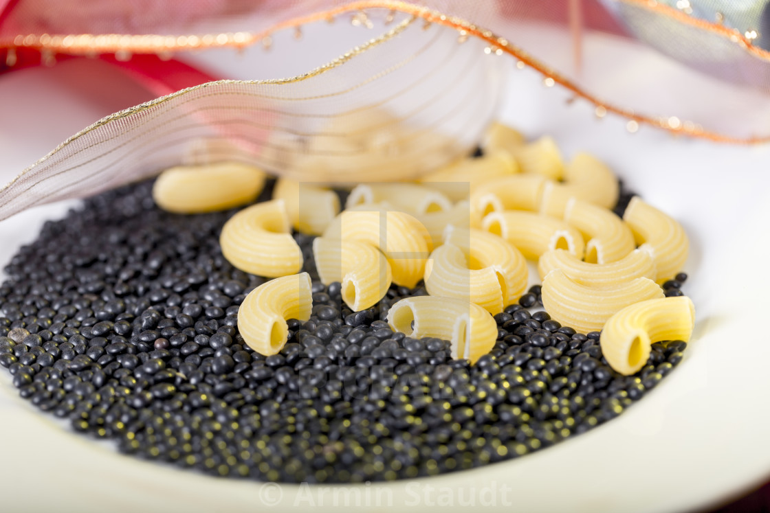 raw pasta and black beluga lentils on a white plate - License, download or  print for £ | Photos | Picfair