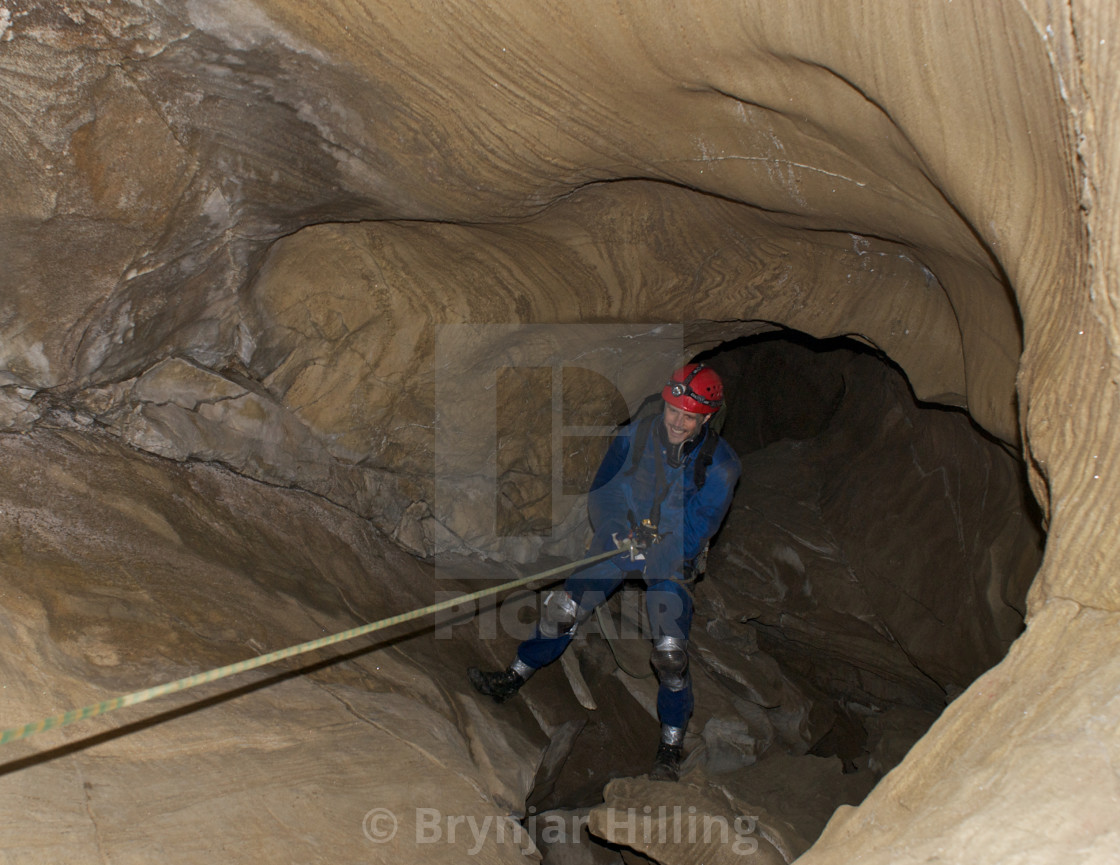 "Man rapelling in cave." stock image