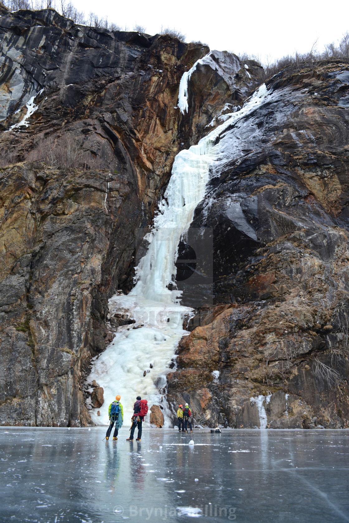 "Men looking at frozen ice-fall" stock image