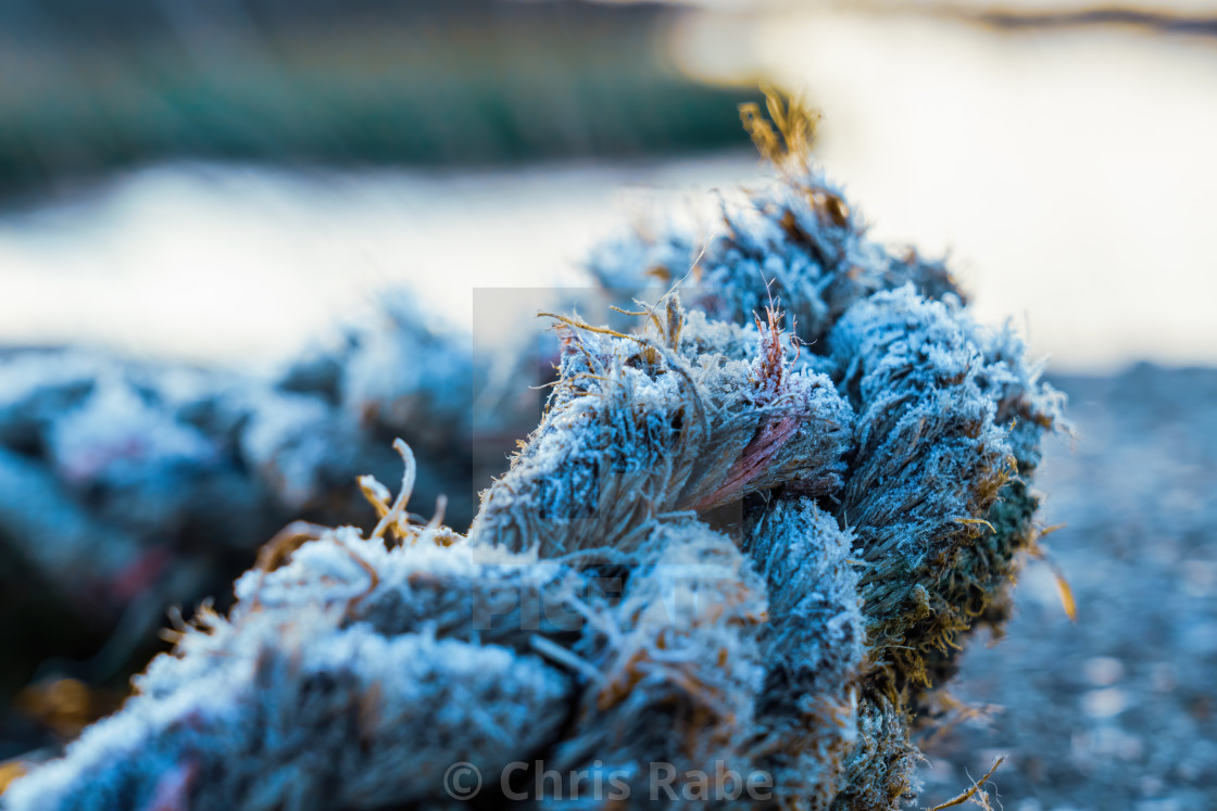 "Thick rope covered in ice from a heavy frost in winter, diiscarded next to..." stock image