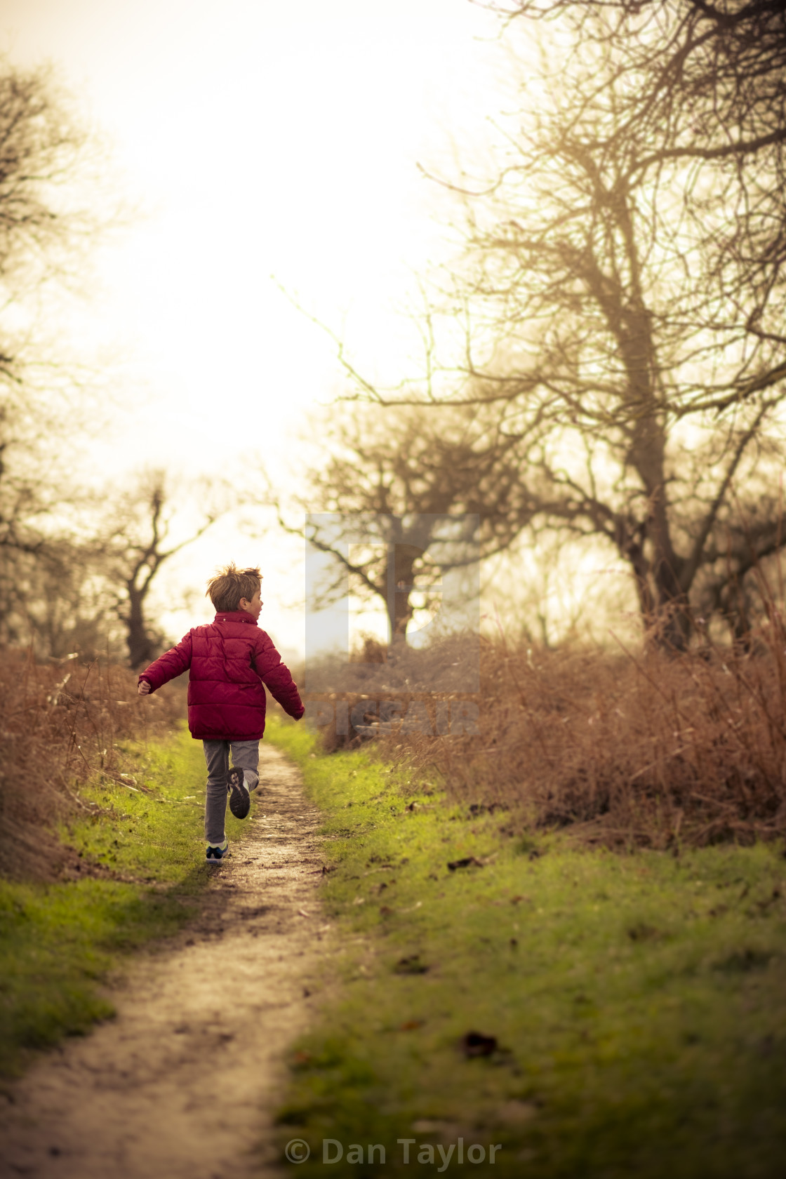 "Boy Running down path in winter sun" stock image