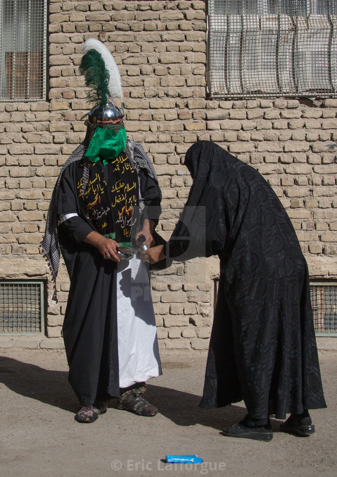 A Man dressed as Imam Hussein gives water to a woman on Tasua ...