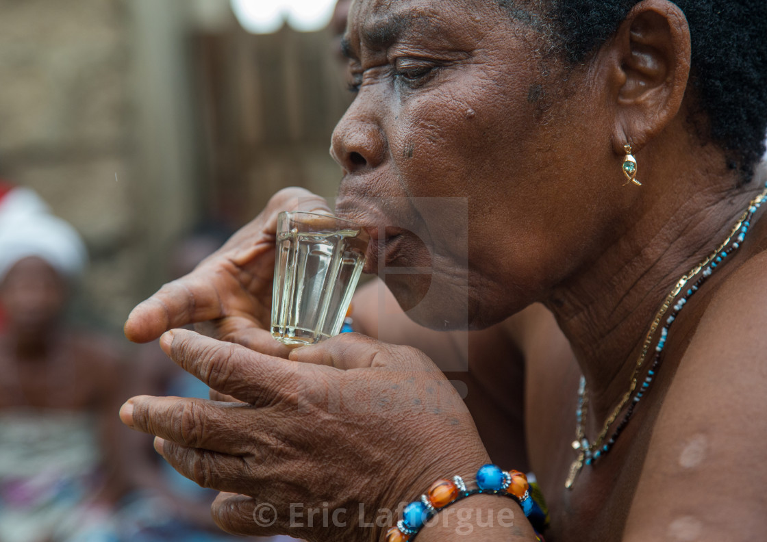 "Benin, West Africa, Bopa, woman drinking alcohol during a voodoo ceremony" stock image