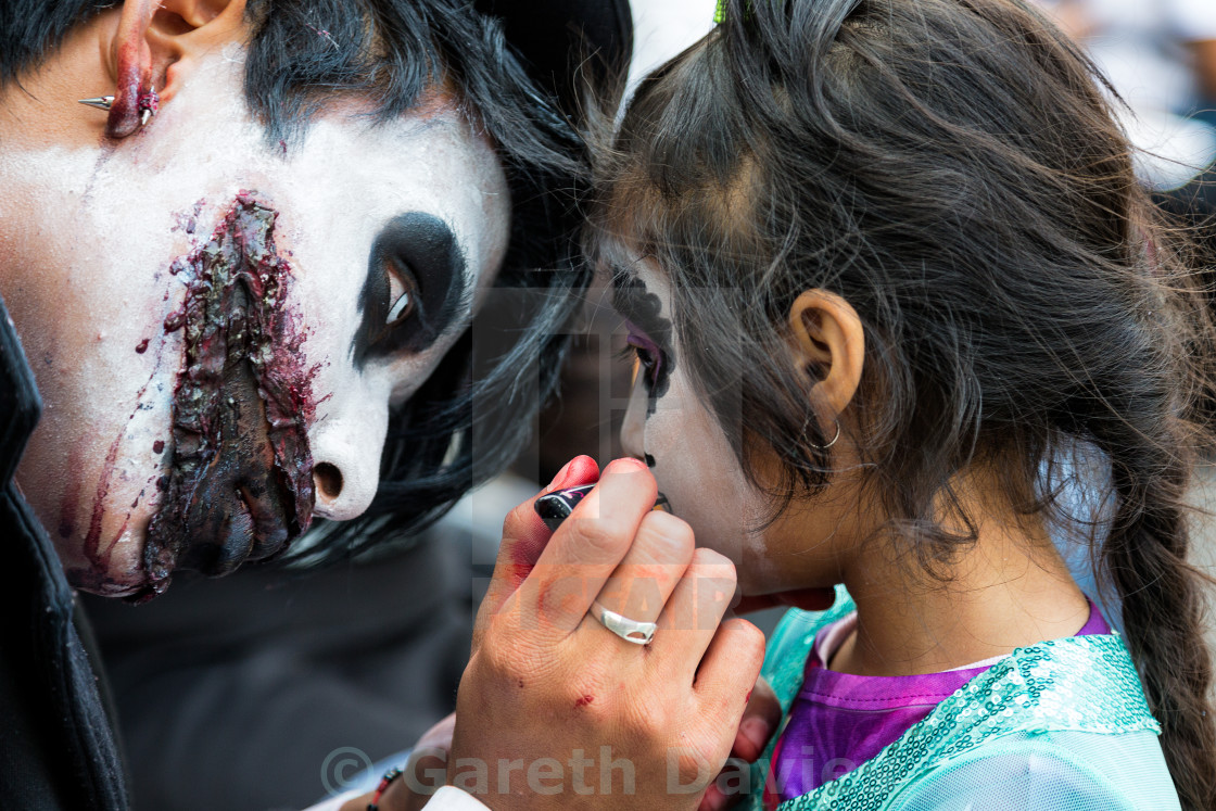 "A young man paints his daughters face for day of the dead celebrations in mexico" stock image