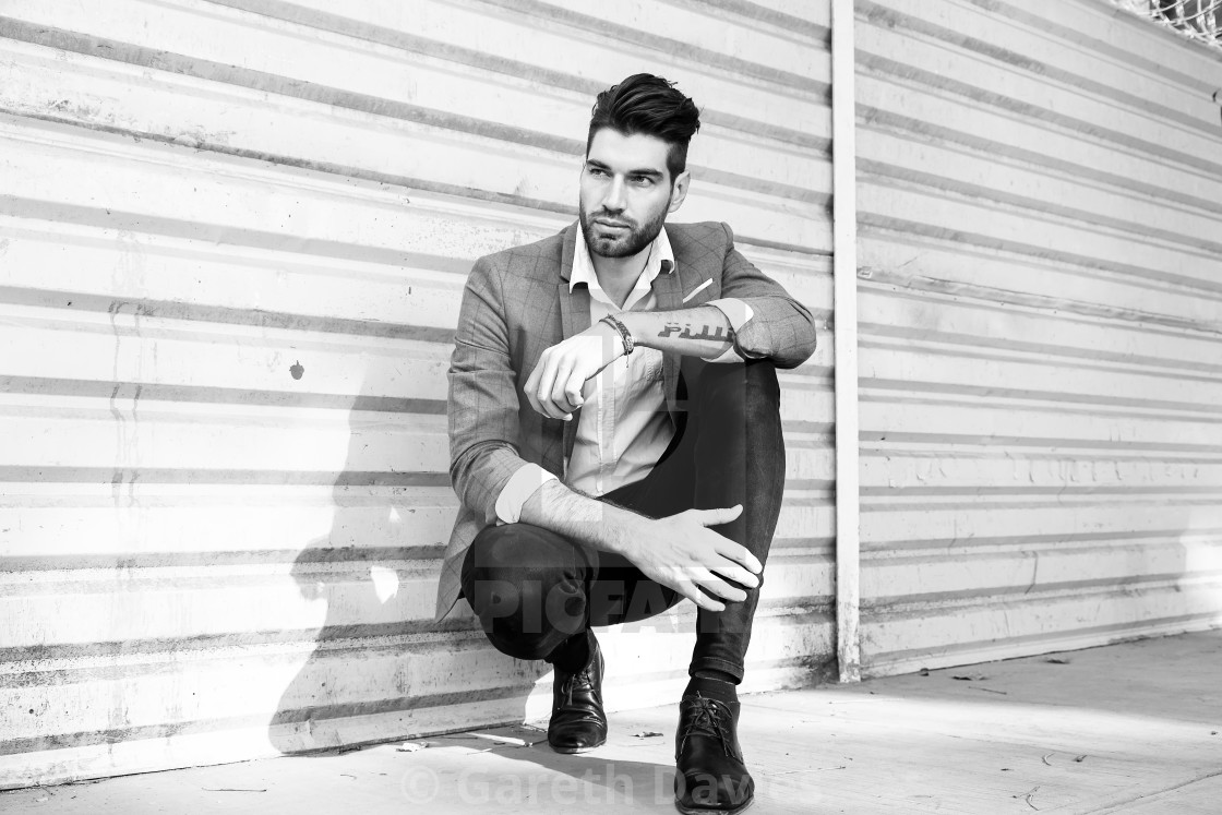 "A male fashion model crouching down in an urban setting in a black and white photograph" by Gareth Davies - $77.88 "A male fashion model crouching down in an urban setting in a black and white photograph" stock image