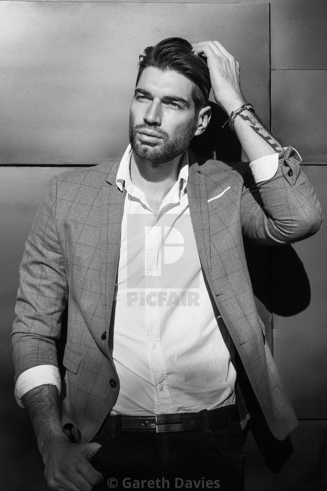 "A black and white photo of a male fashion model standing against a wall adjusting his hair" by Gareth Davies - $77.88 "A black and white photo of a male fashion model standing against a wall adjusting his hair" stock image