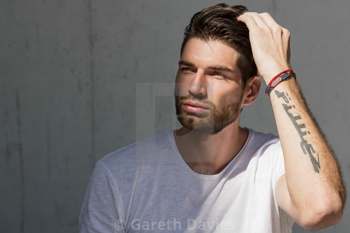 "A male fashion model running his in a white t shirt running his hand through his hair" by Gareth Davies - $77.88 "A male fashion model running his in a white t shirt running his hand through his hair" stock image