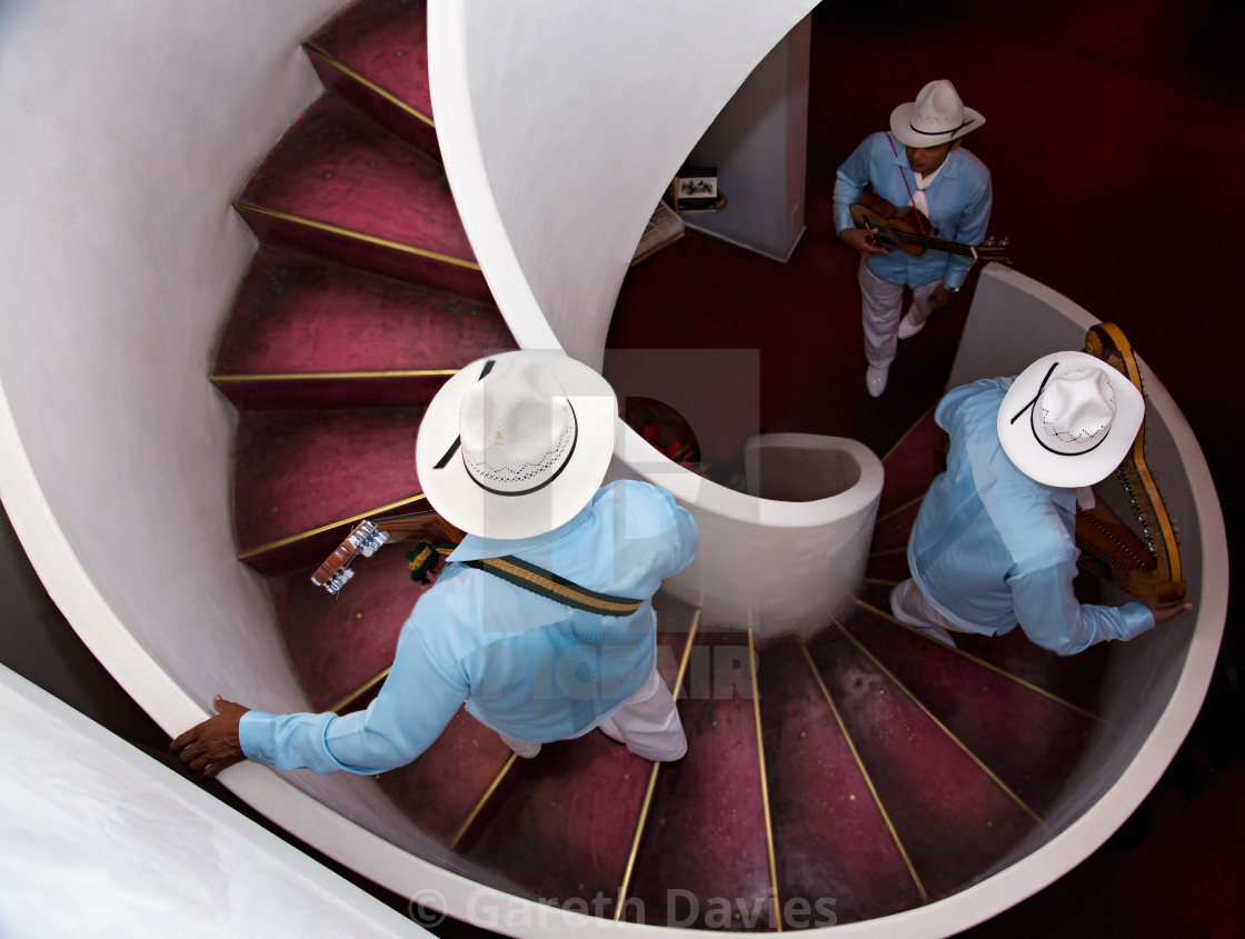 "A Mexican trio going up a spiral staircase to play music" stock image