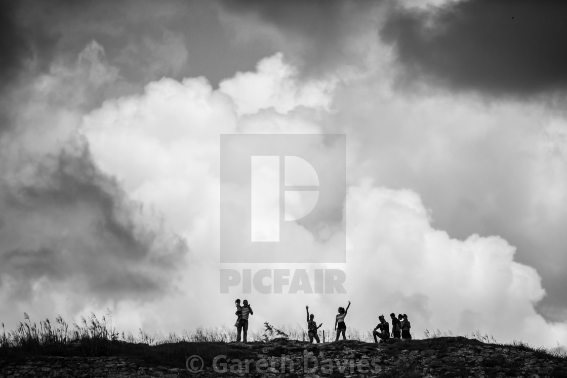 "a group of people stand on a ridge with dramatic clouds behind them" by Gareth Davies - $7.79 "a group of people stand on a ridge with dramatic clouds behind them" stock image
