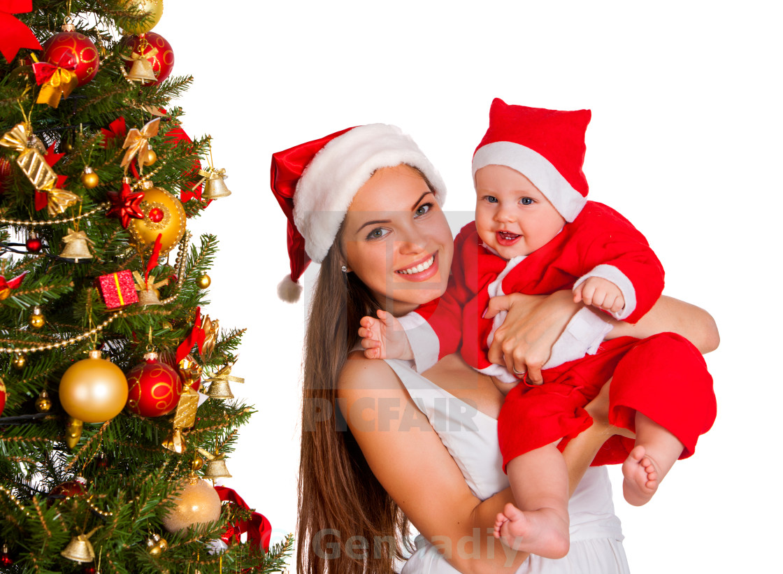 Mom Wearing Santa Hat Holding Baby Under Christmas Tree License