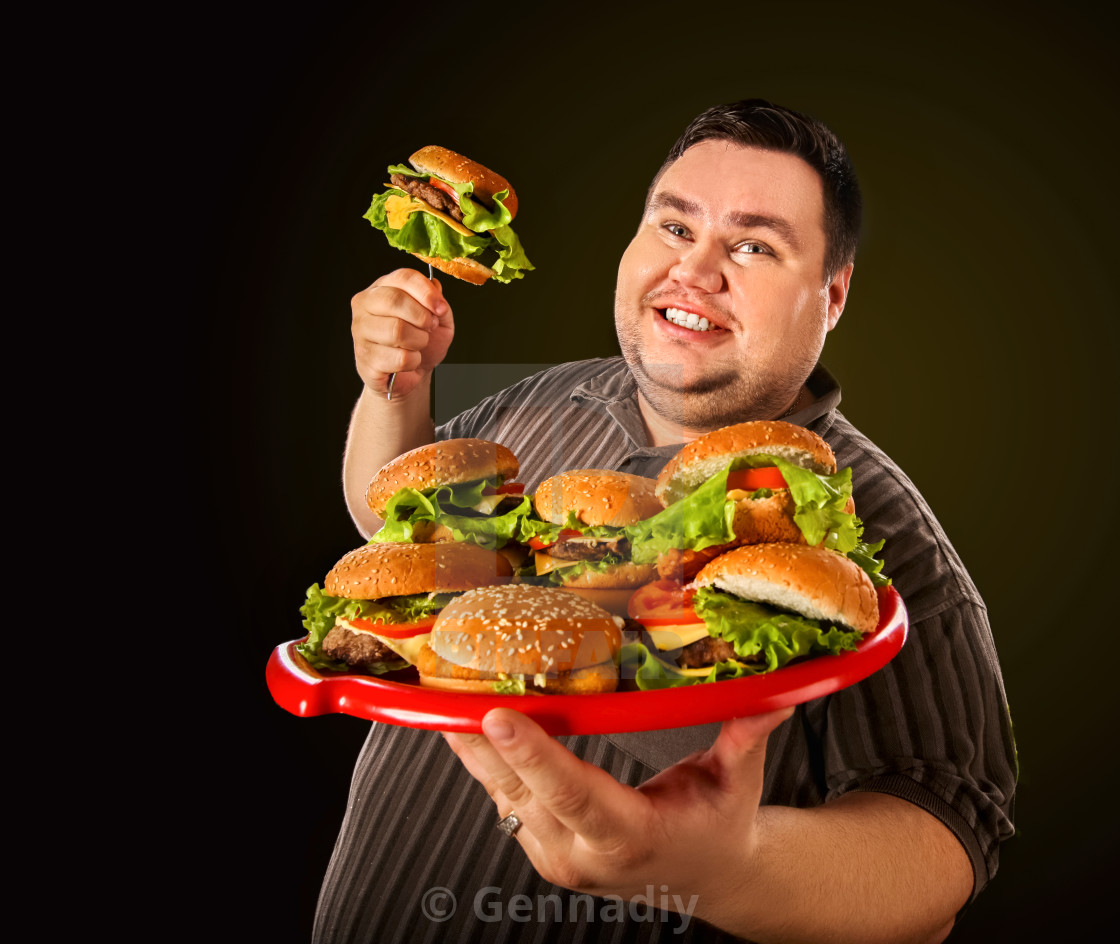 Fat man eating fast food hamberger. Breakfast for overweight person ...