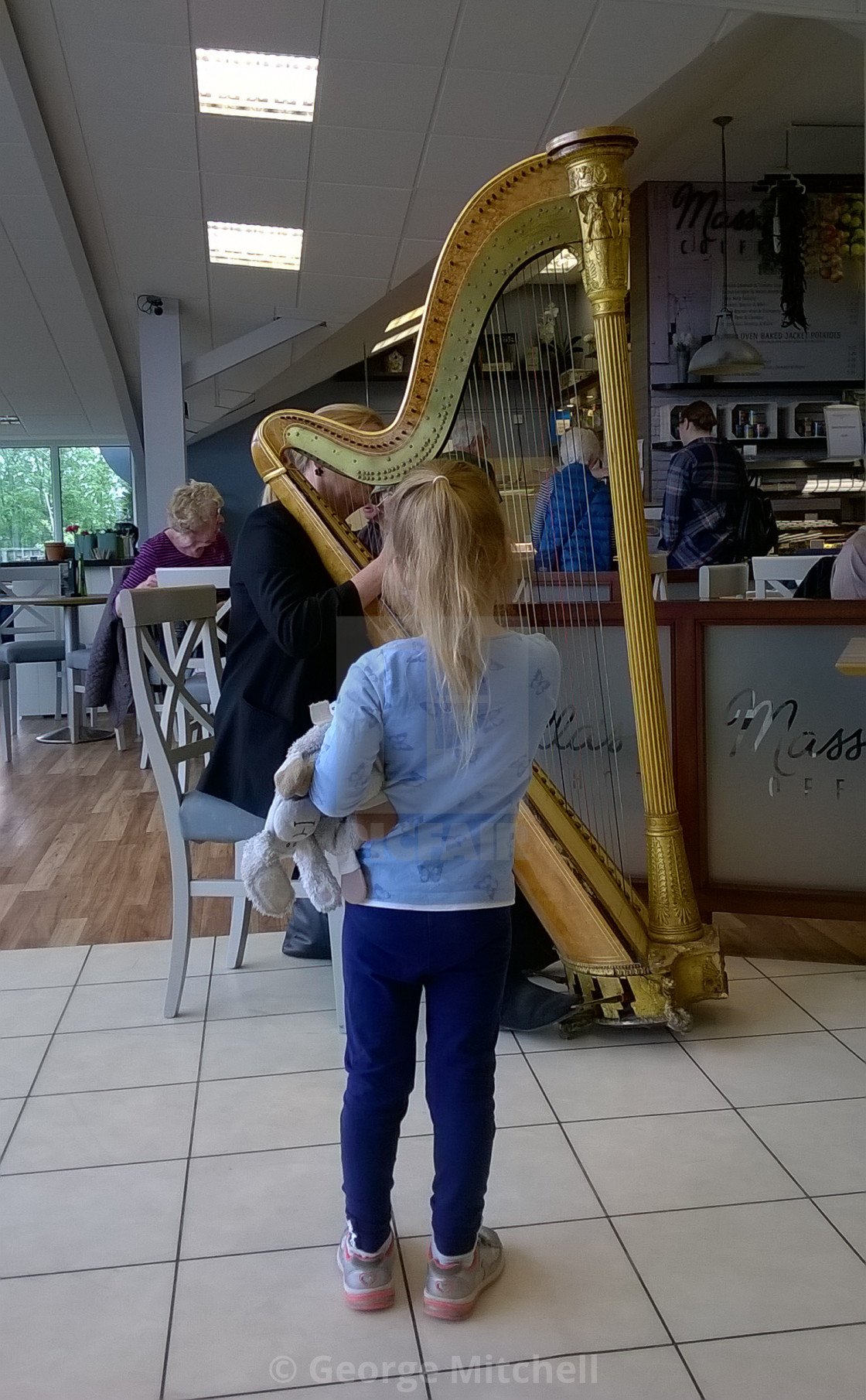 "Young child watching harpist giving a recital, Cambridge,UK" stock image