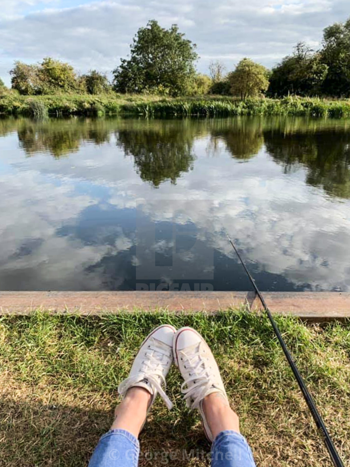 "Young lady sitting on bank fishing" stock image