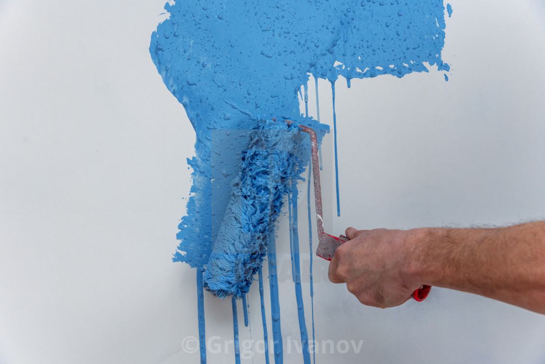 Male Hand Painting Wall In Blue With Paint Roller License For