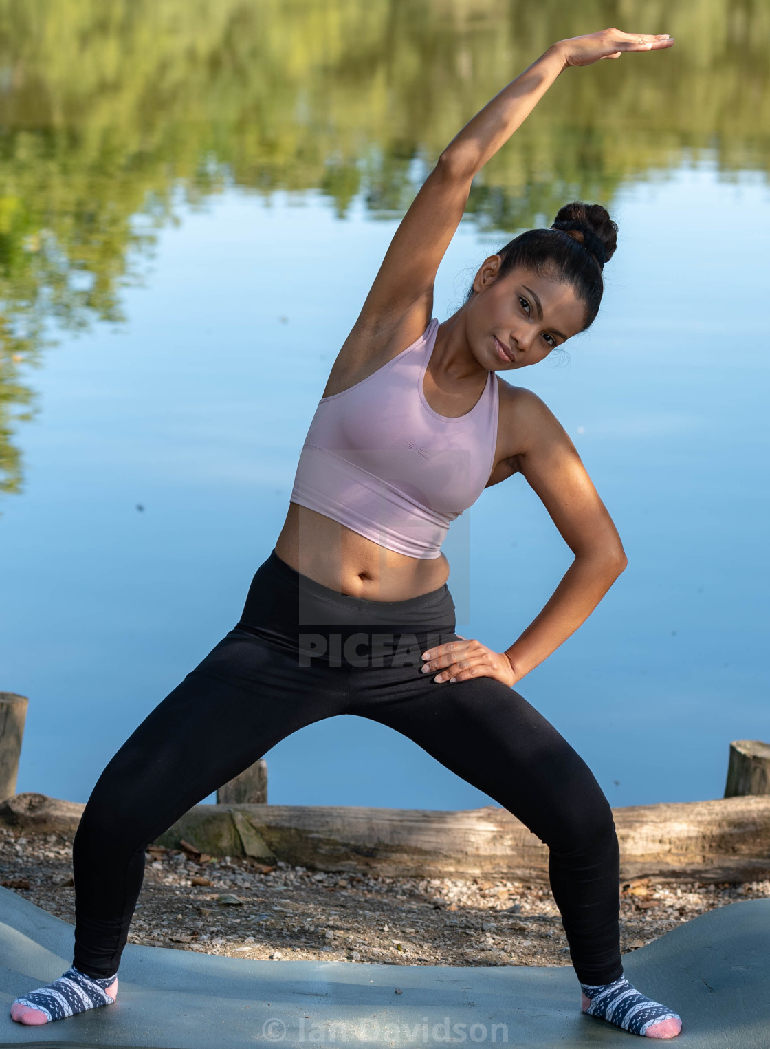 "Young woman performs yoga by lake" stock image