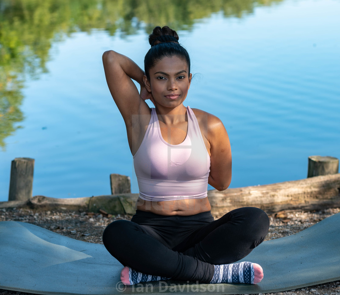 "Young woman performs yoga by lake" stock image