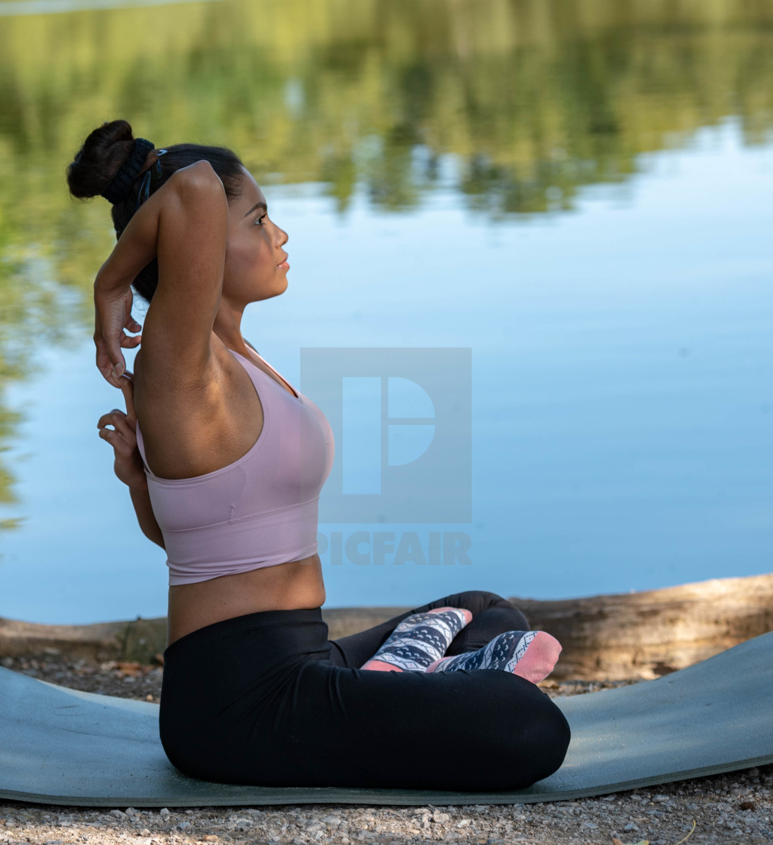 "Young woman performs yoga by lake" stock image