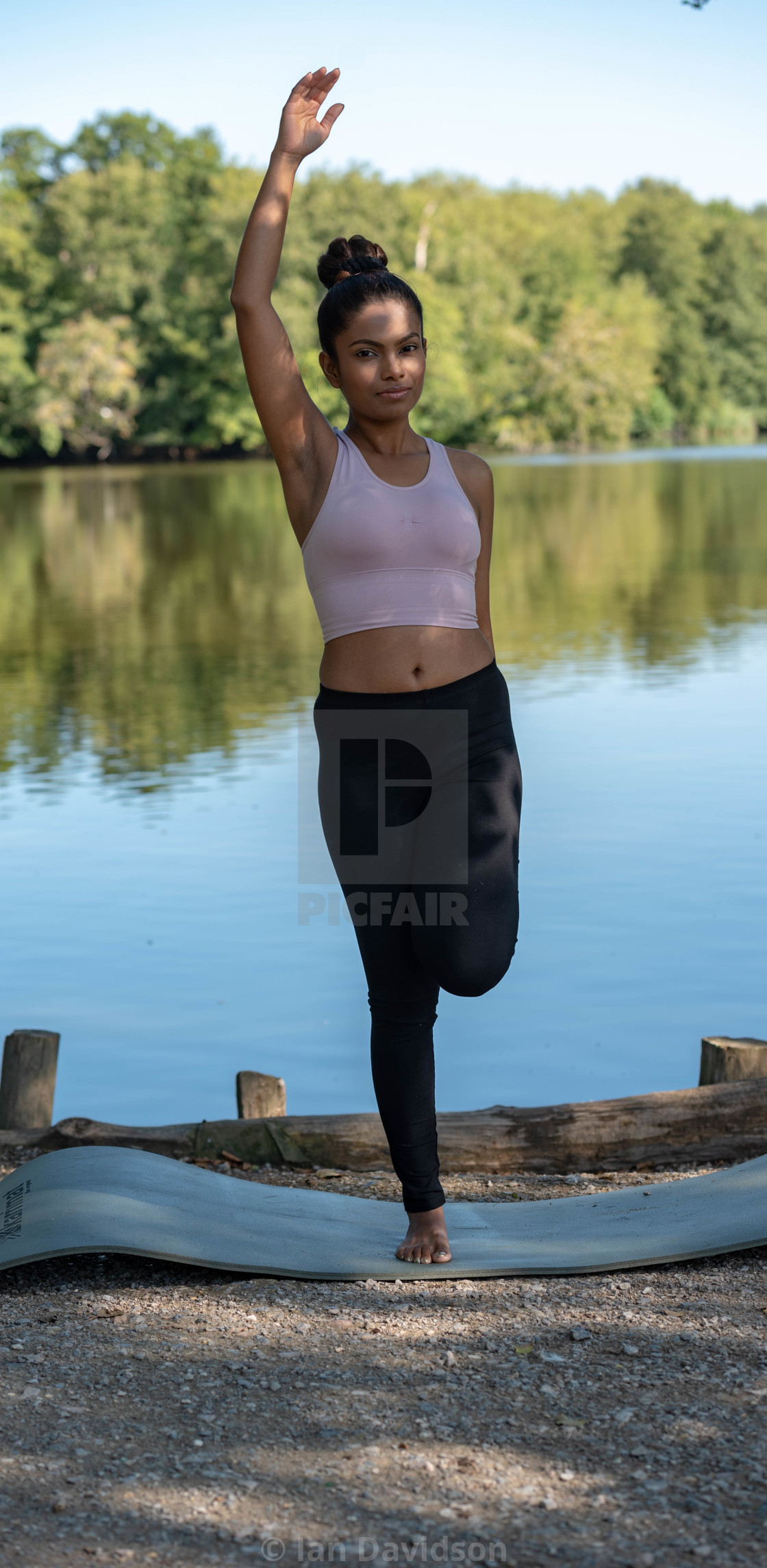 "Young woman performs yoga by lake" stock image