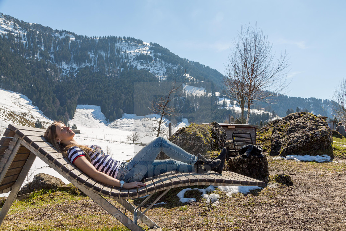 "Beautiful girl lying on the wooden chair in the nature with mountains on the..." stock image