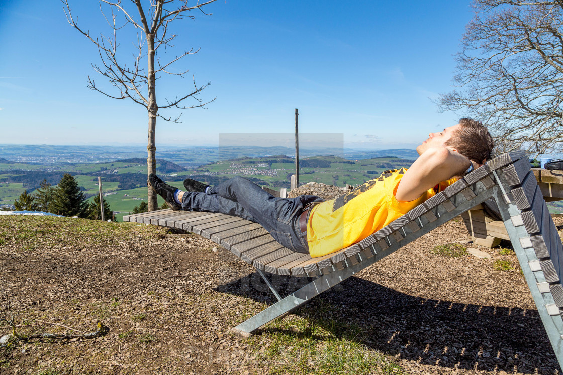 "Young man lying on the wooden chair in the nature. Successful person." stock image