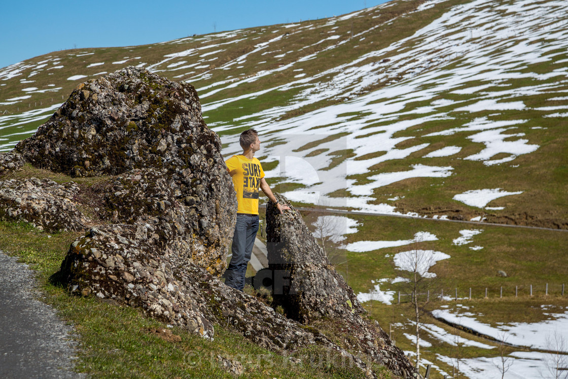 "Young man standing among rocks in Swiss mountains, hiking." stock image