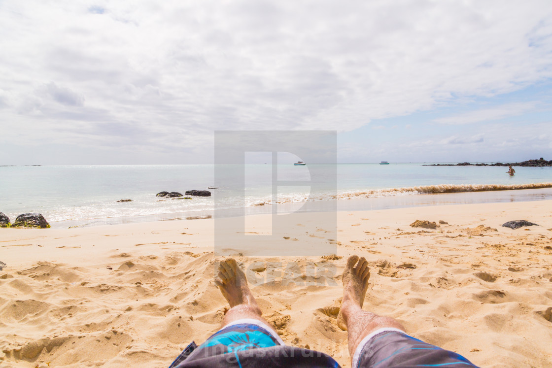 "Close up of a young man feet relaxing on the beach with the sea in the..." stock image