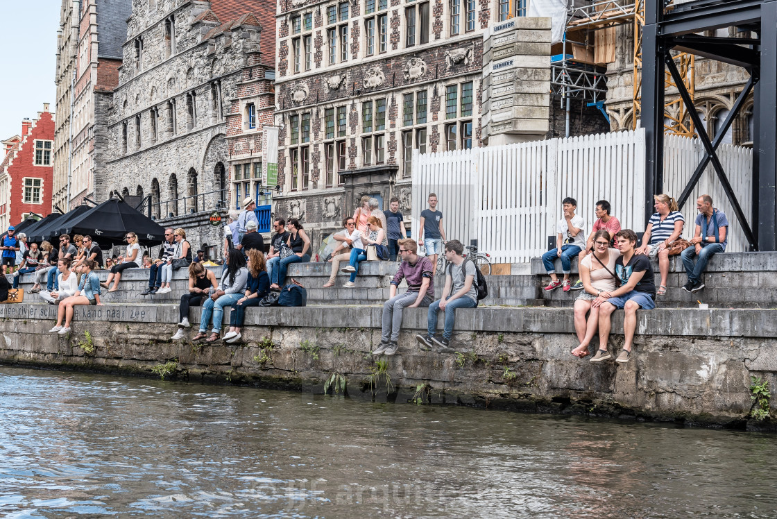 "A crowd of students sitting on riverside of Embankment Graslei i" stock image