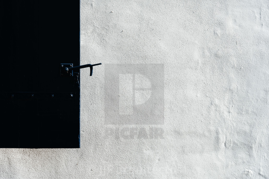 "Close up of a black shutter on a white plaster covered wall in o" stock image