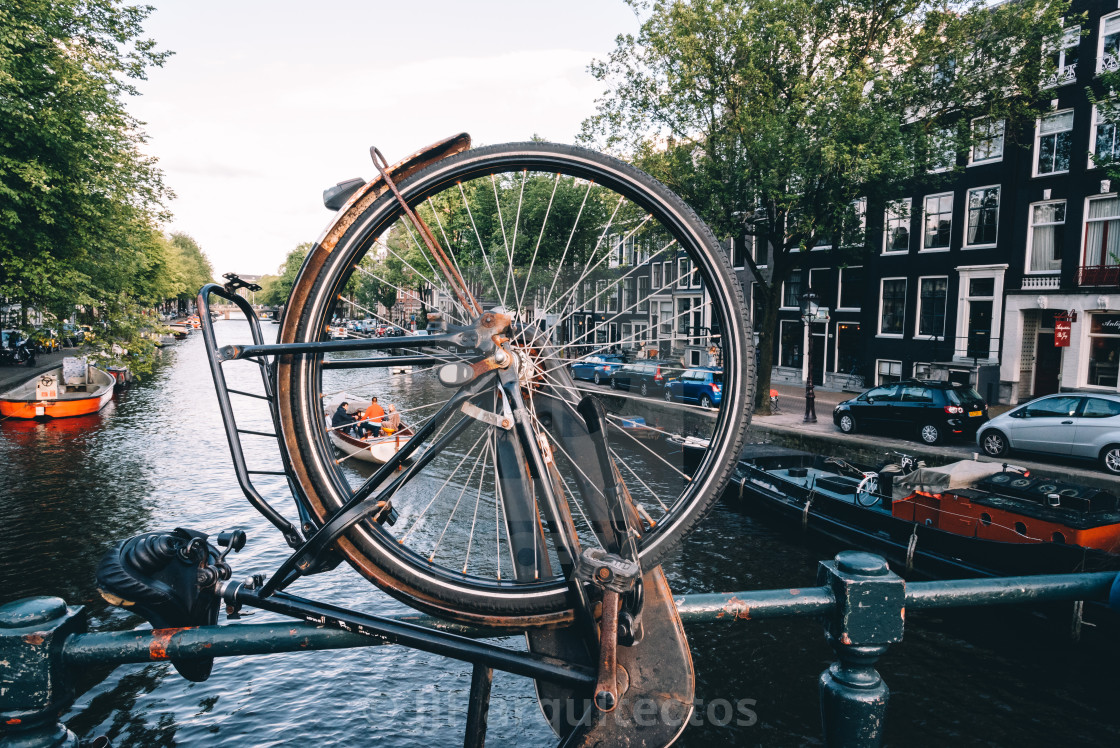 "Canal view in Amsterdam, view through bicycle wheel parked on br" stock image