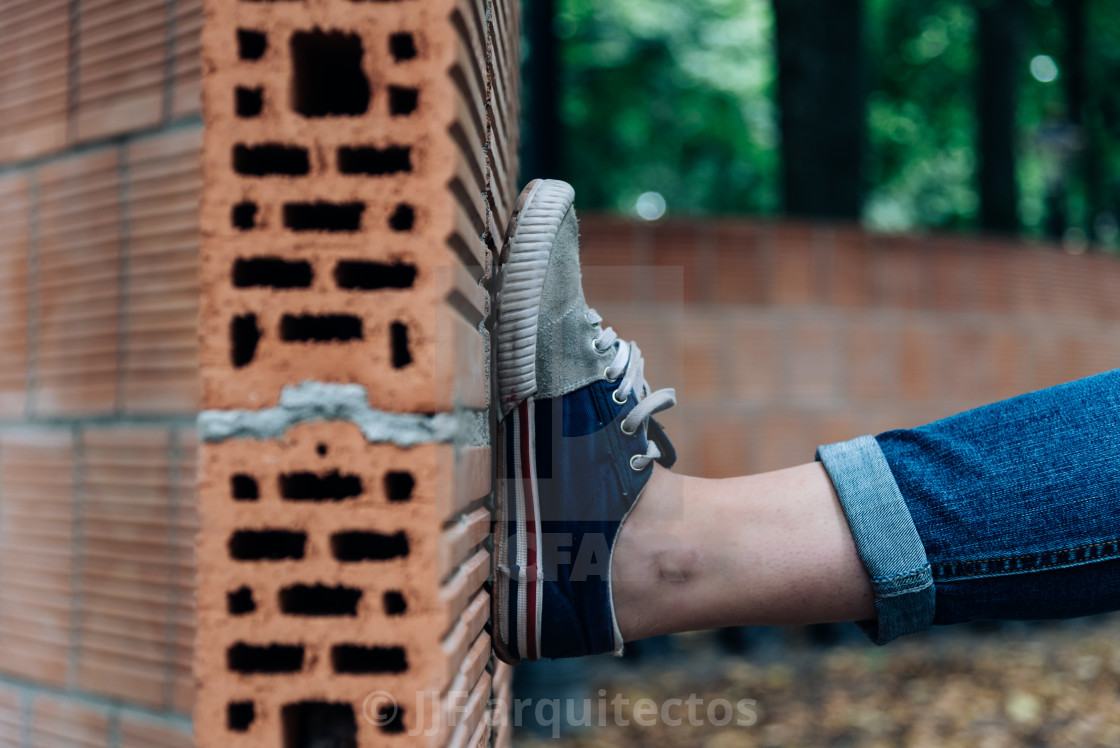 "Woman wearing sneakers leaning his foot on curved brick wall in" stock image