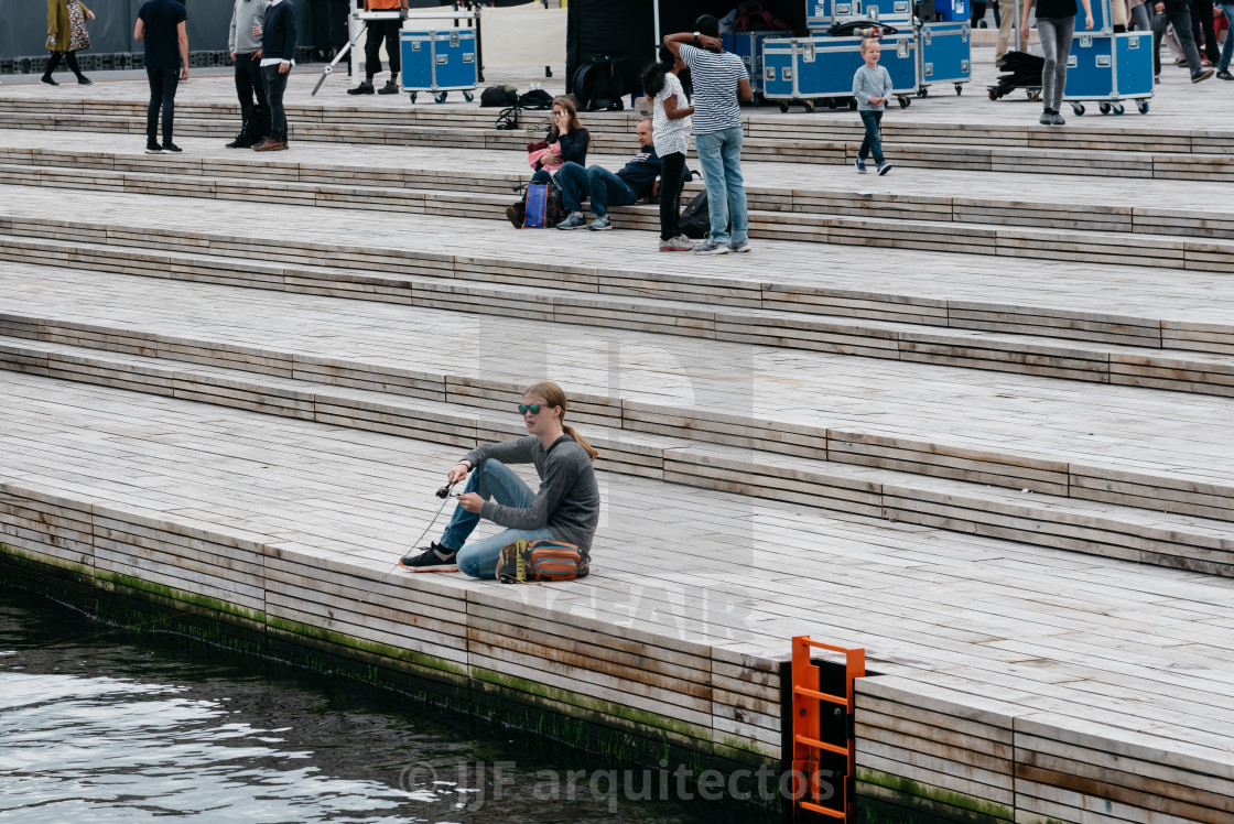 "Young woman fishing sitting on the pier of the port of Copenhage" stock image