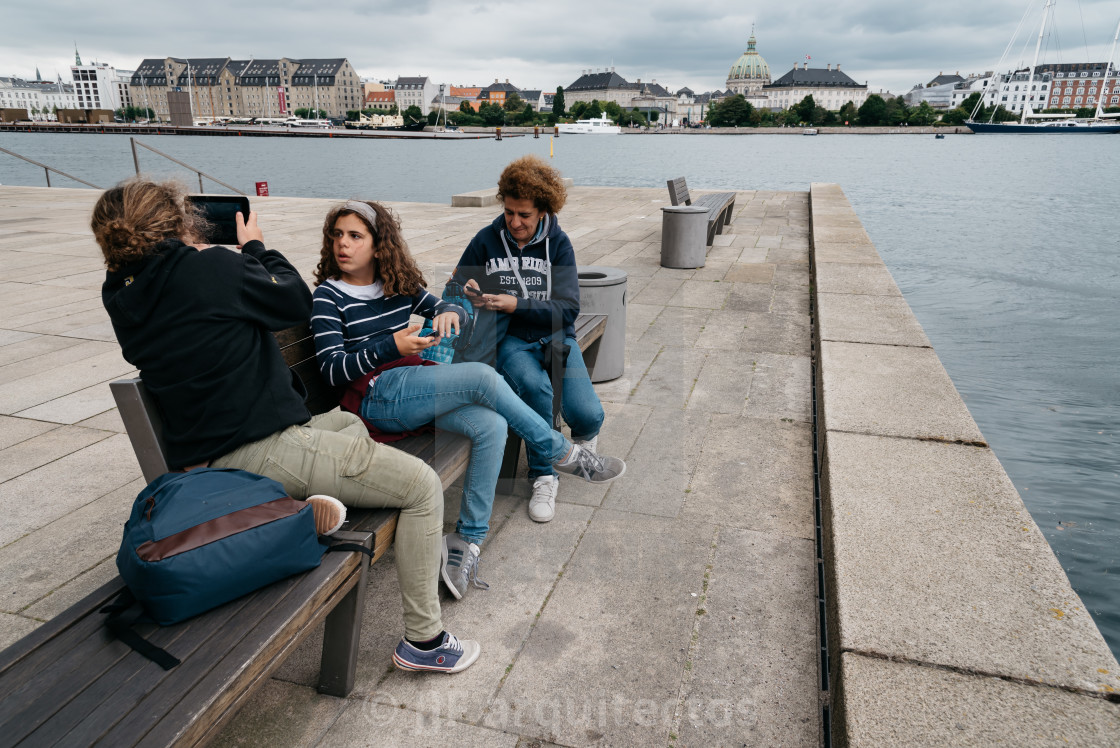 "Unidentified family of tourists sitting on a bench against Copen" stock image