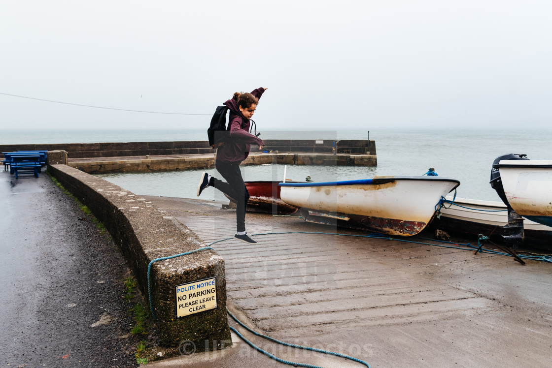 "Woman wearing casual clothes jumping at harbor in Irish coast" stock image