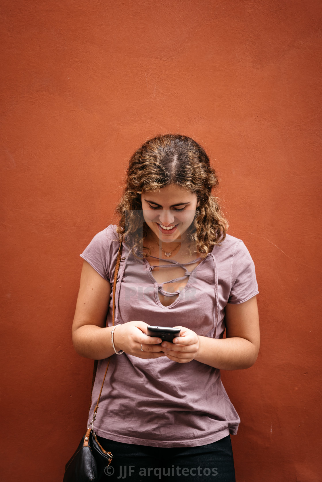 "Beautiful young woman smiling texting on her smart phone" stock image