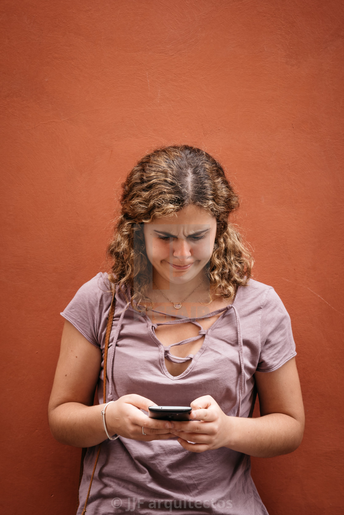 "Beautiful young woman with weird face texting on her smart phone" stock image