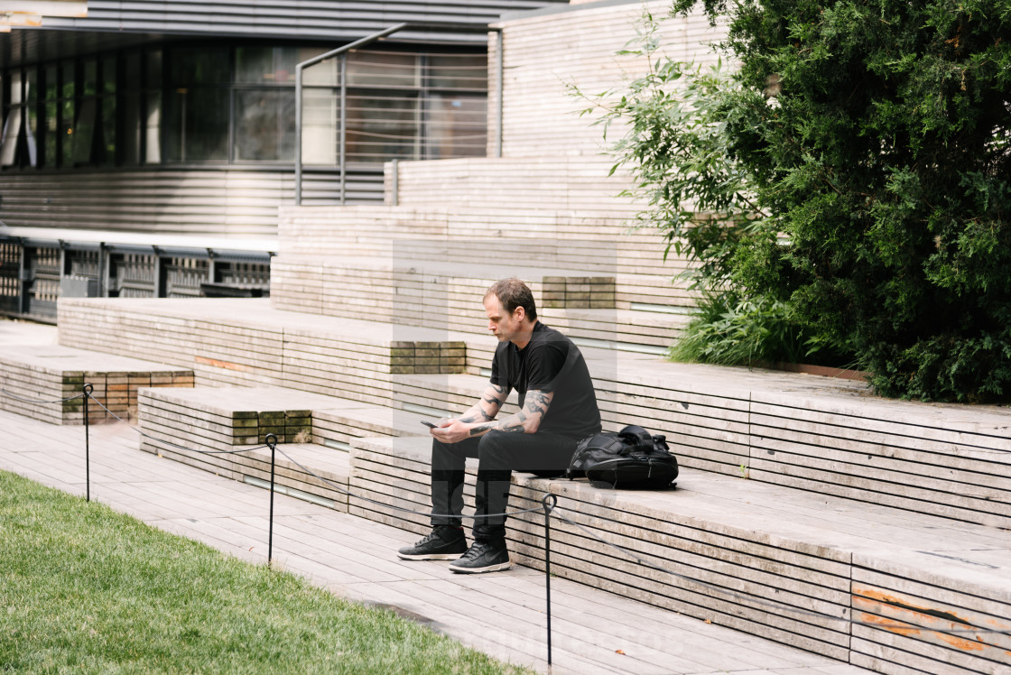 "Man with smartphone sitting on steps in High Line" stock image