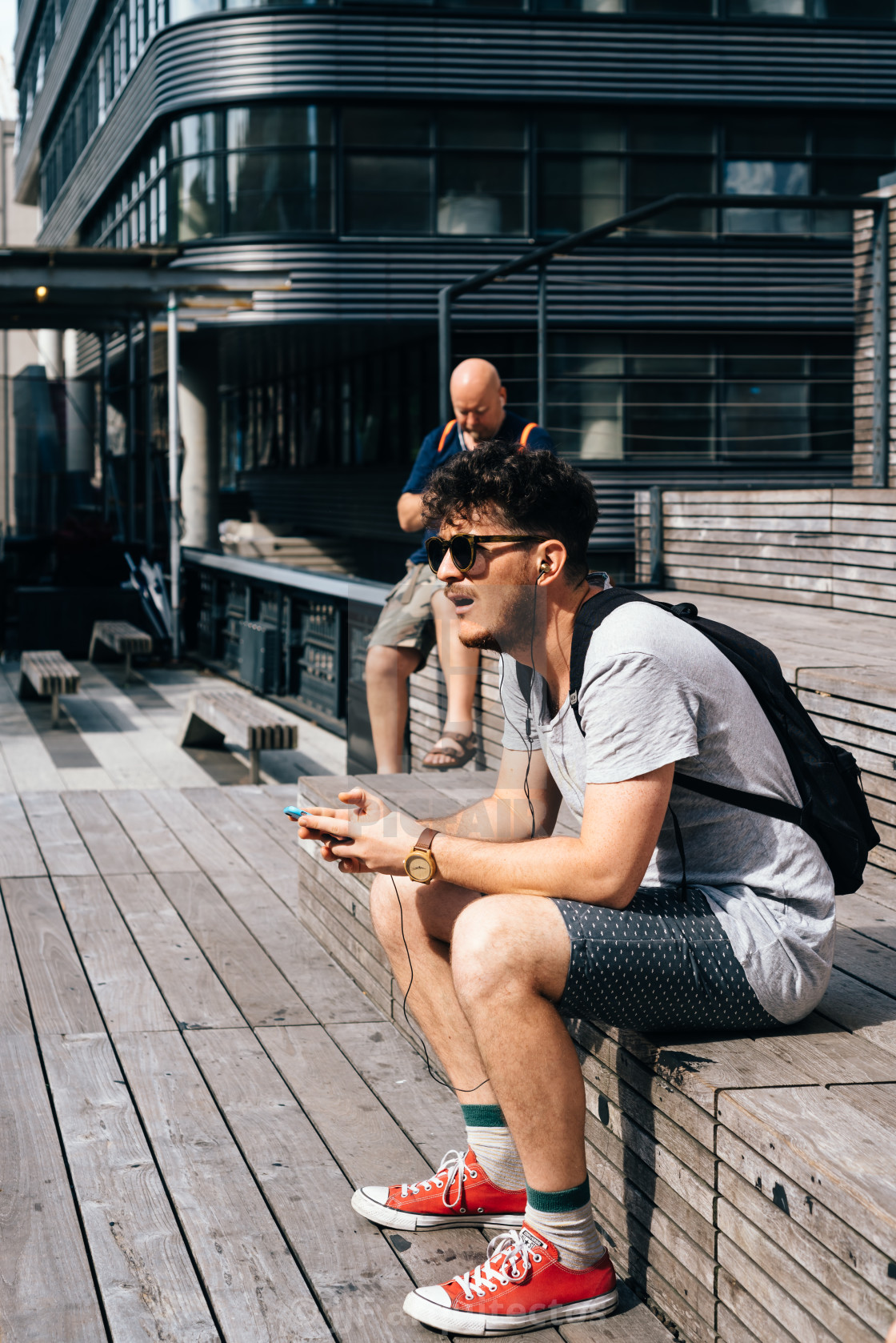 "Man with smartphone sitting on steps in High Line" stock image